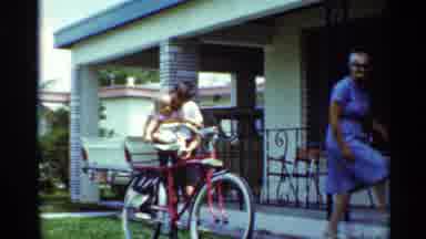Mississippi (1963): Woman Holding Baby On Bike Seat In The Front Yard Of House