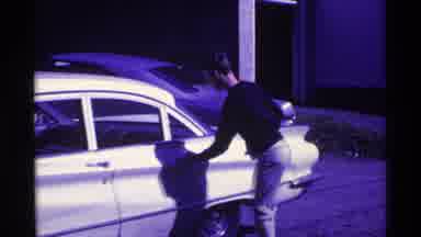 Ohio USA (1969): Man Wearing Black Shirt Gets Into White Car On A Bright Sunny Day