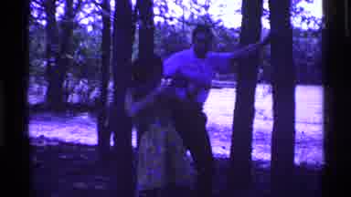 Ohio USA (1969): Woman Aims Gun In Woods As Man Looks On While Leaning Against