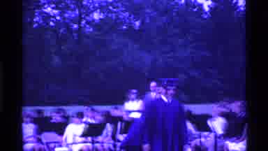 Ohio USA (1969): Man In Cap And Gown Walking In A Graduation Ceremony With Crowd