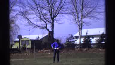 Florida Michigan (1970): A Man Is Standing Outside With Trees And Houses In The