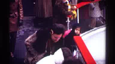 New York City (1970): A Mother Wearing A Coat While In A Crowd Stoops To Pick Up A