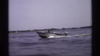 New York (1973): A Blue And White Boat Driving Quickly Across An Open Lake
