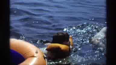 New York (1973): Child Wearing Life Vest Swims In Water On A Bright Sunny Day