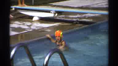 New York (1973): Girl Wearing Orange And Yellow Swim Cap Swims To Side Of Pool