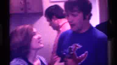 Kentucky (1976): Woman Holding Microphone Talks To Red Headed Man Wearing Blue