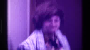 Kentucky (1976): Woman Wearing Blue Plaid Coat Waves Folded Money At Camera