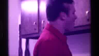 Kentucky (1976): A Man With A Red Shirt Talking In A Room With Cabinets On The