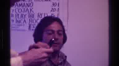 Kentucky (1976): Man Wearing Brown And White Shirt Talks Into Black Microphone