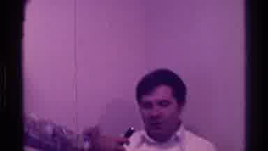 Kentucky (1976): Woman Wearing Blue Dress Hands Black Microphone To Man Wearing