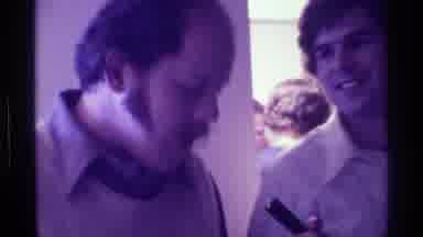 Kentucky (1976): Man In Yellow Vest Talking To Microphone Held By Man In White
