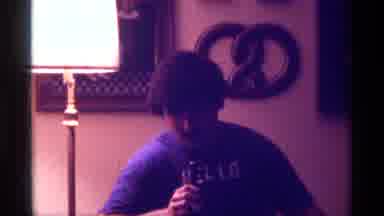 Kentucky-1976: A Man Speaking Into a Microphone in a Dimly Lit Room