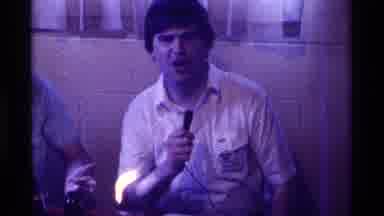 Kentucky (1976): Men Talking Into A Microphone In Front Of People At A Party