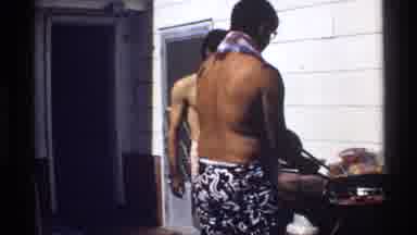 California (1978): A Shirtless Man Cooks Food On An Outdoor Grill While People Sit