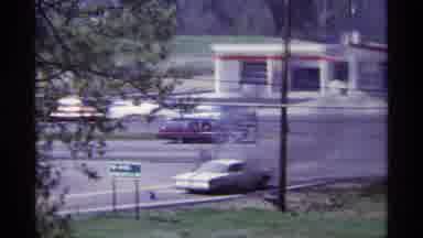 Chicago Illinois (1968): White Car On Side Of Road Burning While Cars Pass By