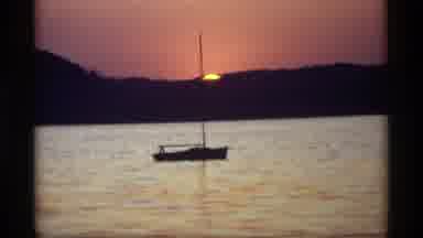 Holland Michigan (1969): A Sailboat Sitting On Calm Water At Sunset With The Mast