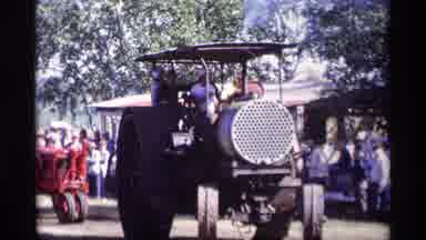 Jordan Minnesota (1969): Multiple Tractors Carrying People Drive In Field Near