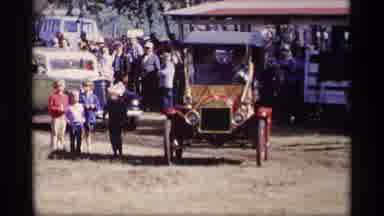 Jordan Minnesota (1969): Old Cars Driving Along A Dirt Path With Many People