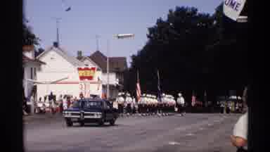 Mabel Minnesota (1969): Marching Parade Down A Straight Road With Car And A Float