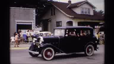 Mabel Minnesota (1969): Black Car In A Parade Followed By A Float With Women