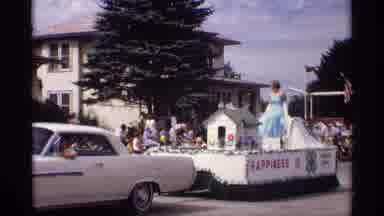 Mabel Minnesota (1969): Woman In A Blue Dress Riding On A Parade Float And Waving