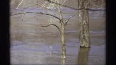 Savage Minnesota (1969): Red Car Drives By Flooded Road On A Clear Day
