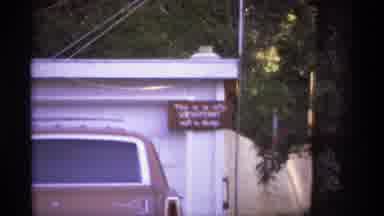 Spokane (1974): View Of Brown Car Parked In Front Of White Garage On A Clear Day