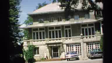 Minnesota (1970): Large House With Two Cars Parked Outside And A Long Driveway
