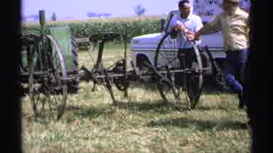 Minnesota (1971): Man Wearing Green Shirt Looks At Vintage Grey Combine On A Sunny