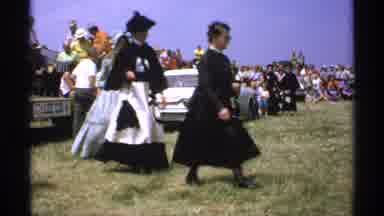 Minnesota (1971): Women Walking Daytime Following In Line Hats Outside Man Running