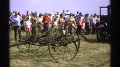 Minnesota (1971): Green Truck Follows Black Vintage Combine Machine On A Clear Day