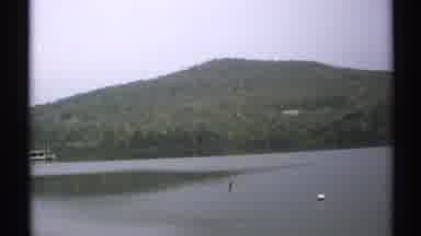 New York (1971): Serene Still Water Mountain Lake With Green Tree Covered Hill In