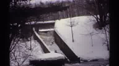 Wisconsin (1971): Icy River Flowing Through Snow Covered Forest In The Midst Of