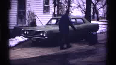 Wisconsin (1971): Man In Coat And Hat Walks Around The Green Car And Opens The