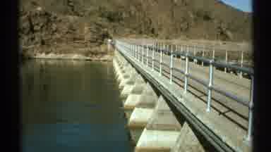 Arizona (1972): Man Standing On Bridge In Front Of River On A Dam