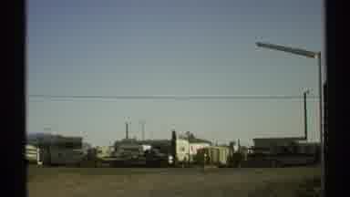 Arizona (1972): In A City Street A Pickup Passes In The Foreground While Numerous
