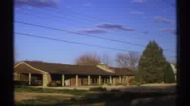 New Mexico (1972): View Of Brown Building Green Tree And Blue Sky With Clouds On A