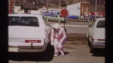 Saint Louis (1972): Woman In A Pink Pant Suit And Matching Scarf Checking Tire