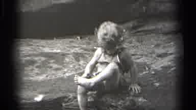 Cleveland Ohio (1938): Child Sitting Outdoors Examines Foot And Points At