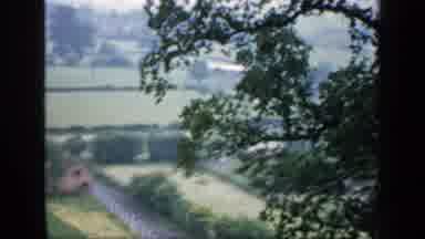 England (1949): View Of Green Farmland And Stone Building On A Cloudy Day