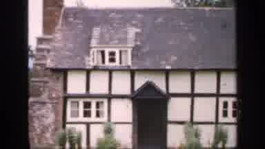 England (1949): Tudor Style Farmhouse With Brick Chimney Next To A Garden Has Roof