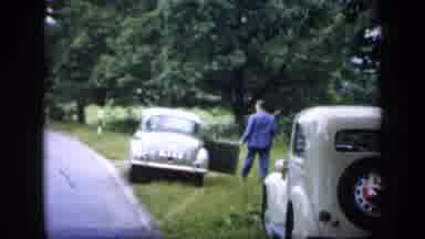 England (1949): Old Classical Car Going In A Street Where People Are Watching The