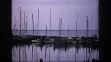 Ireland (1949): Two People Pass By Docked Sailboats On A Clear Day