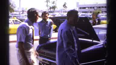 La Paz Mexico (1974): Man Wearing White Shirt Unloads Item From Open Car Trunk