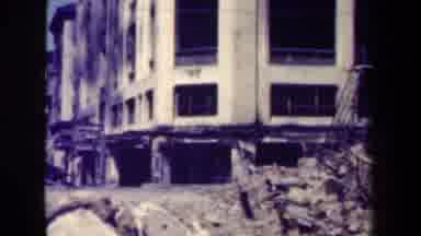MANILLA PHILIPPINES--1944: Black Truck Drives By Damaged White Building On A