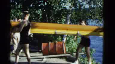 Boston Mass (1951): Men Carrying A Boat Out Of A Body Of Water In Front Of A Red