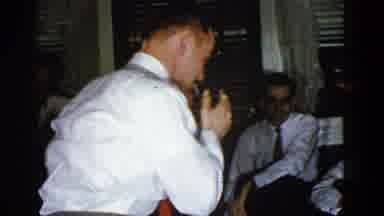 Boston Mass (1951): Man Wearing White Suit Plays Charades On Grey Carpeted Floor