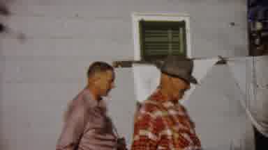 Saint Francis Kansas (1958): Man With Camera Near Man Wearing A Hat Talking To