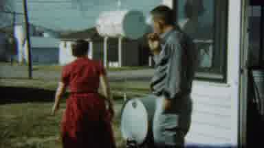 Chadron Nebraska (1959): Woman In Red Dress Walks Away From A Man Smoking A