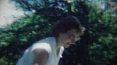 Chadron Nebraska (1959): Woman Wearing White Shirt Looks Down At Ground On A Sunny